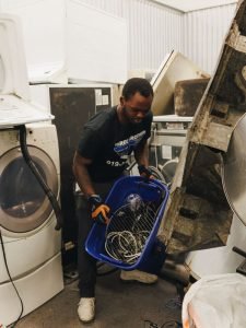 Man in a warehouse holding a basket with electrical wires