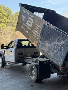 Dump truck with its bed raised, loaded with debris