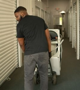 Man moving a dolly with boxes in a storage facility