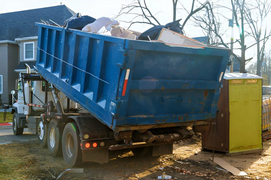 Blue dumpster filled with junk next to a portable toilet, illustrating junk removal services.