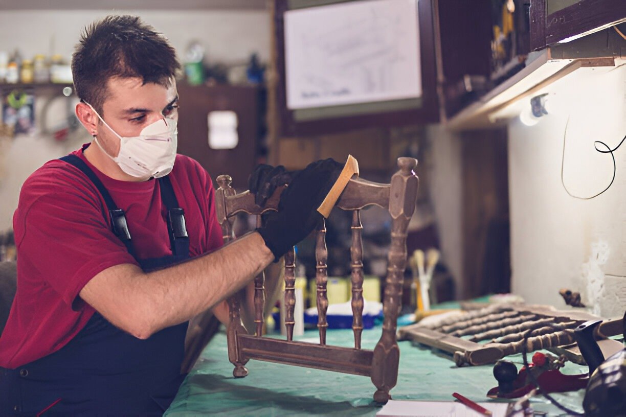 Man in mask refurbishing chair, junk removal in Durham, NC